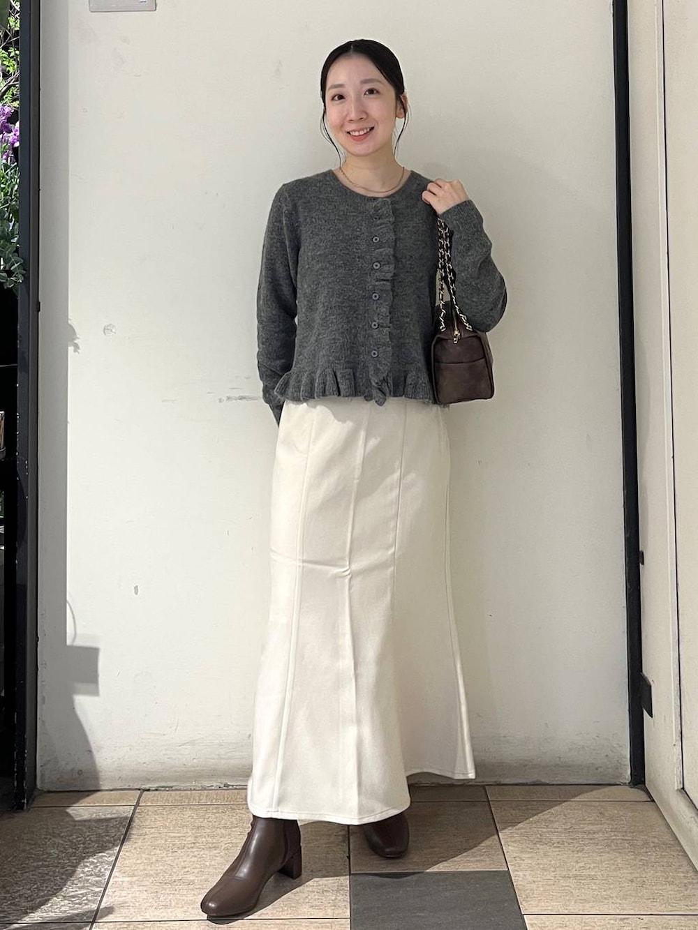 ホワイト系のスカート、ブラウン系のブーツ、グレー系のニット/セーターを着用したレディースの秋コーディネートの2枚目の写真