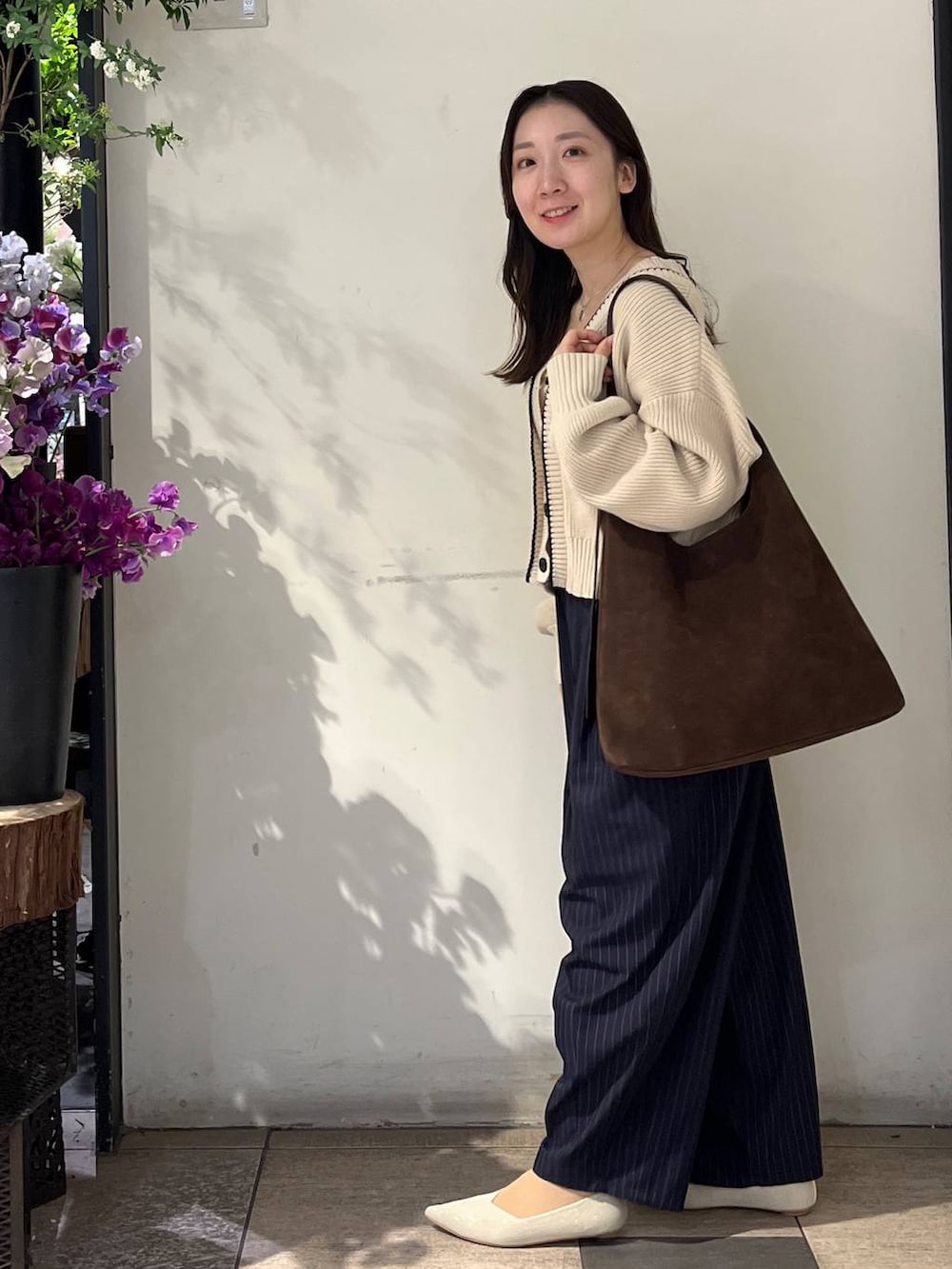 ブラウン系のショルダーバッグ、ブルー系のその他パンツ、ホワイト系のカーディガン/ボレロを着用したレディースの冬コーディネートの3枚目の写真