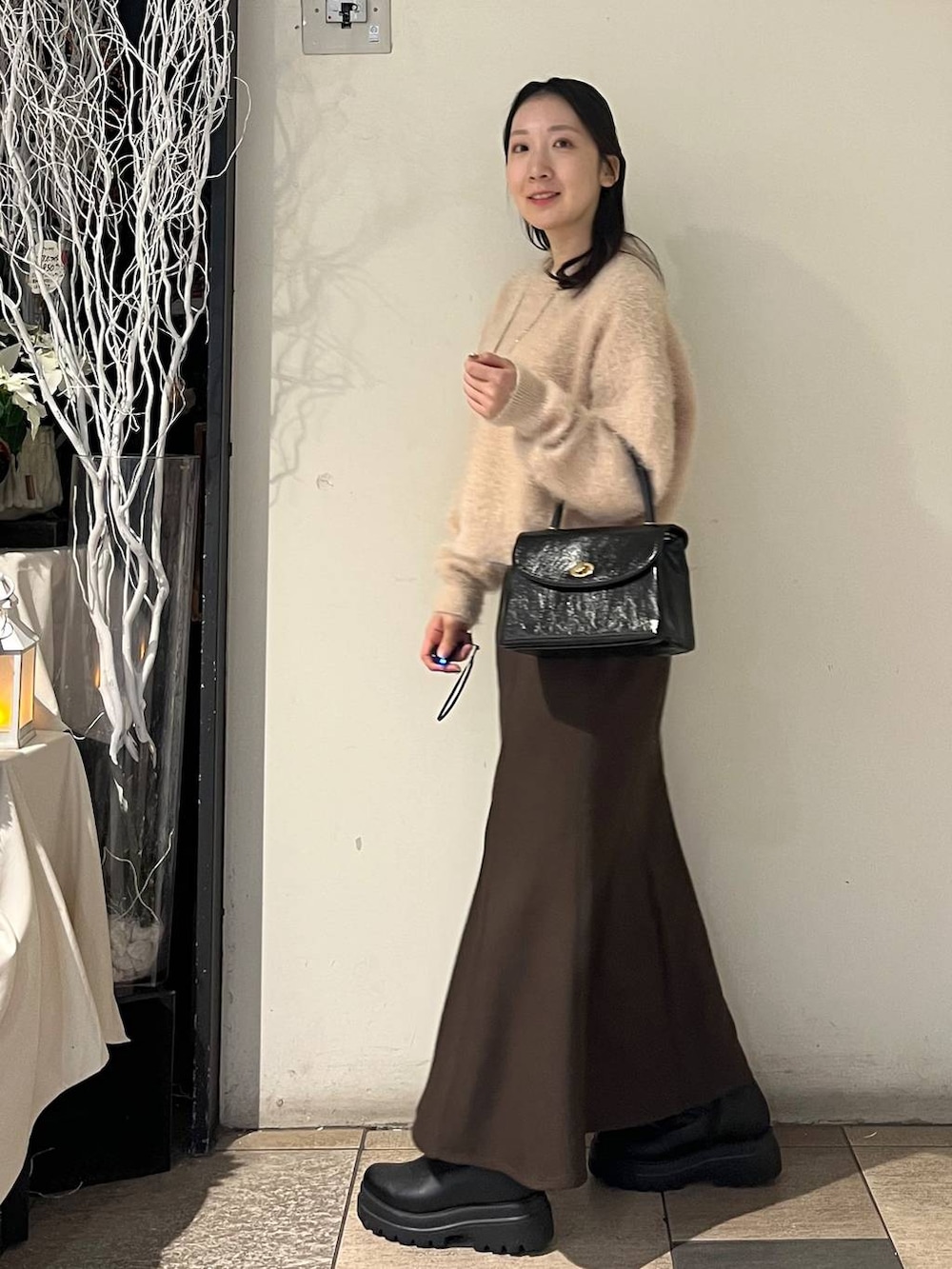 ブラック系のボストンバッグ、ブラウン系のスカート、ブラック系のブーツを着用したレディースの冬コーディネートの5枚目の写真