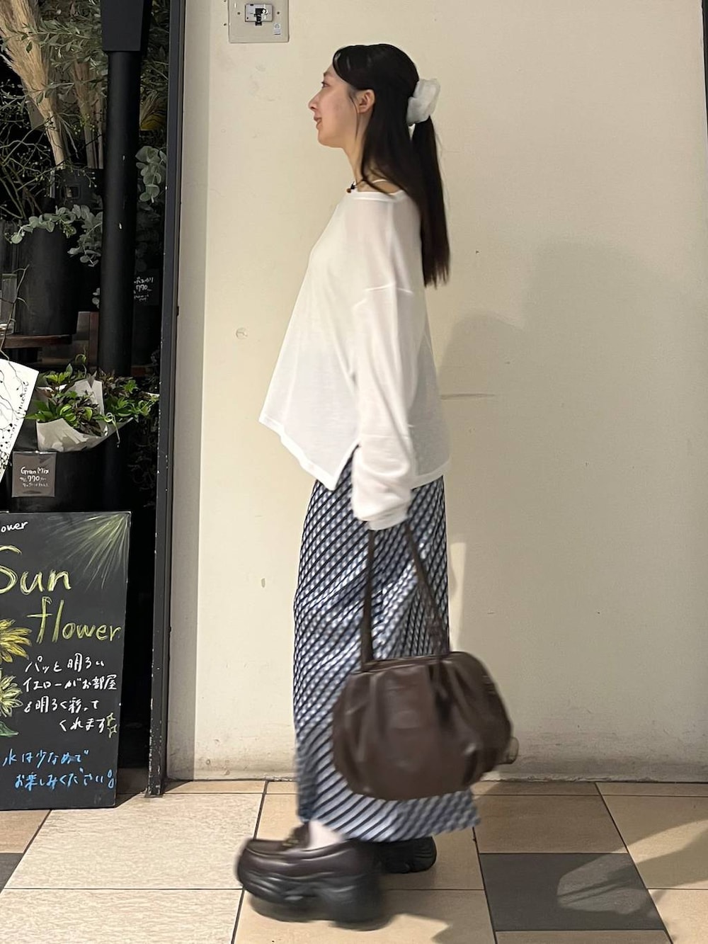 ホワイト系のキャミソール、ブラウン系のボストンバッグ、ブルー系のスカートを着用したレディースの夏コーディネートの3枚目の写真