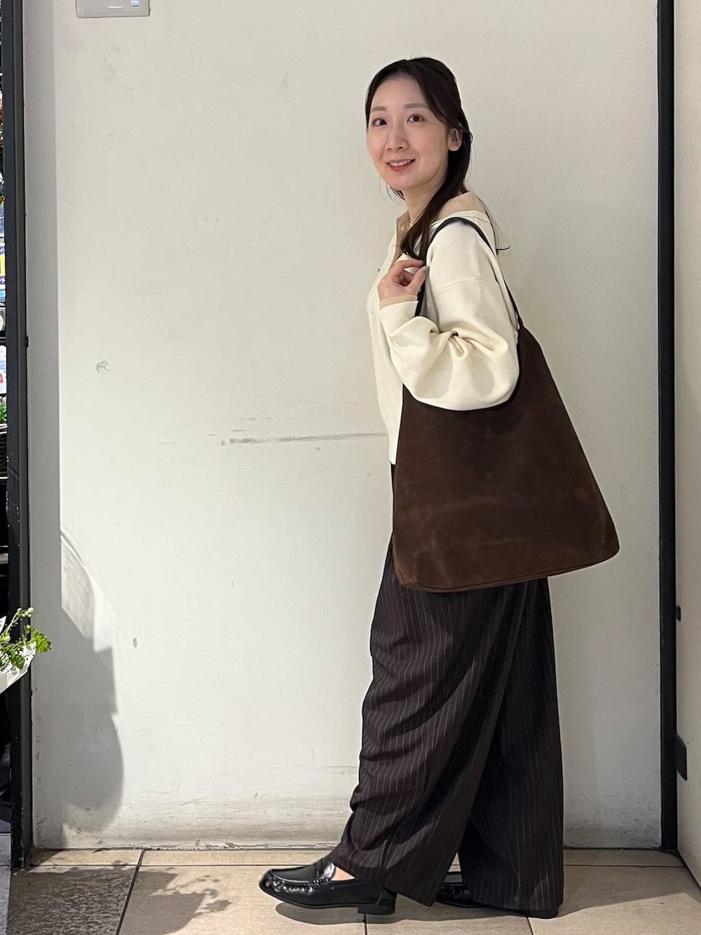 ブラウン系のショルダーバッグ、ブラウン系のその他パンツ、ホワイト系のニット/セーターを着用したレディースの冬コーディネートの3枚目の写真