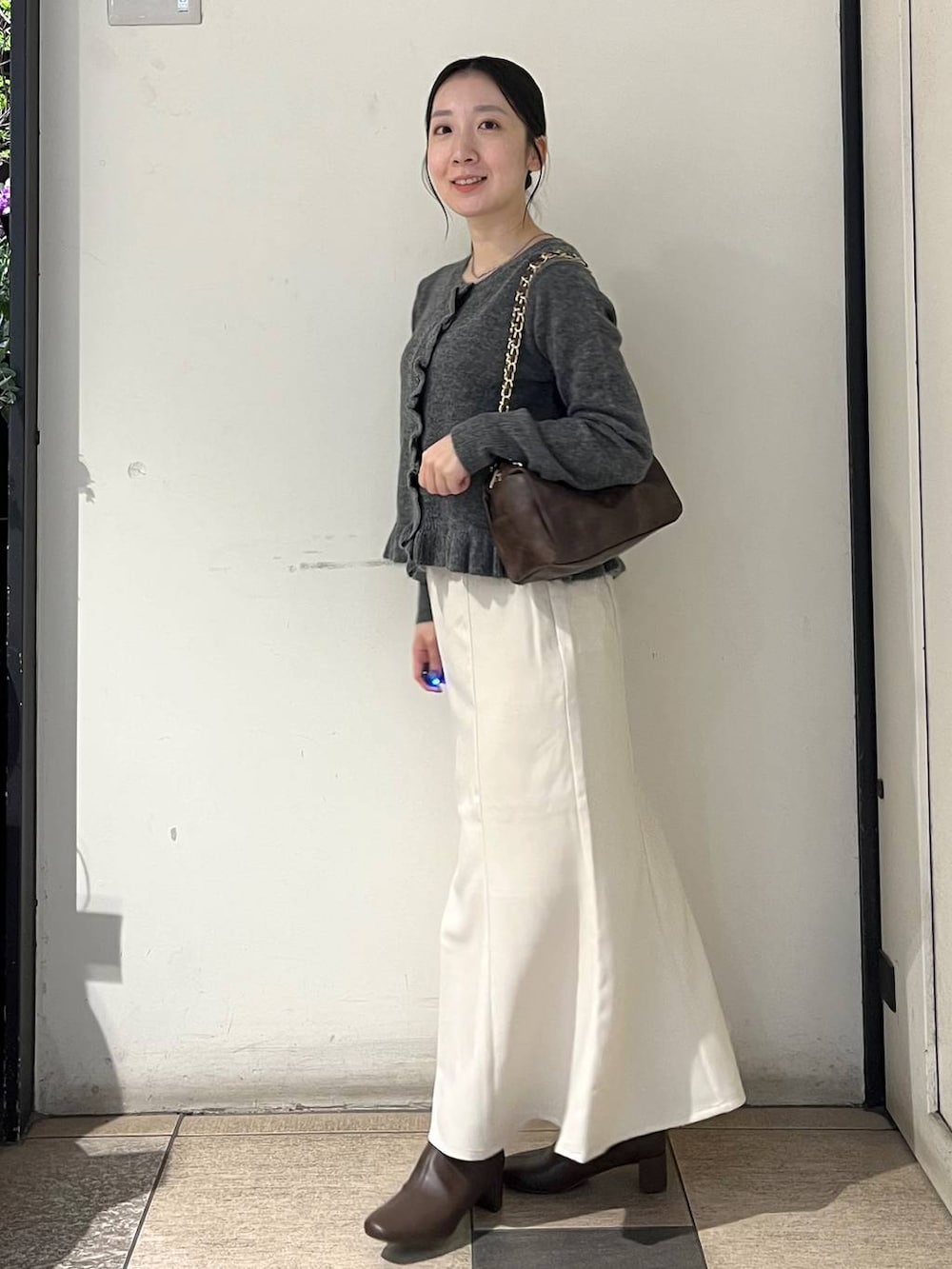 ホワイト系のスカート、ブラウン系のブーツ、グレー系のニット/セーターを着用したレディースの秋コーディネートの3枚目の写真