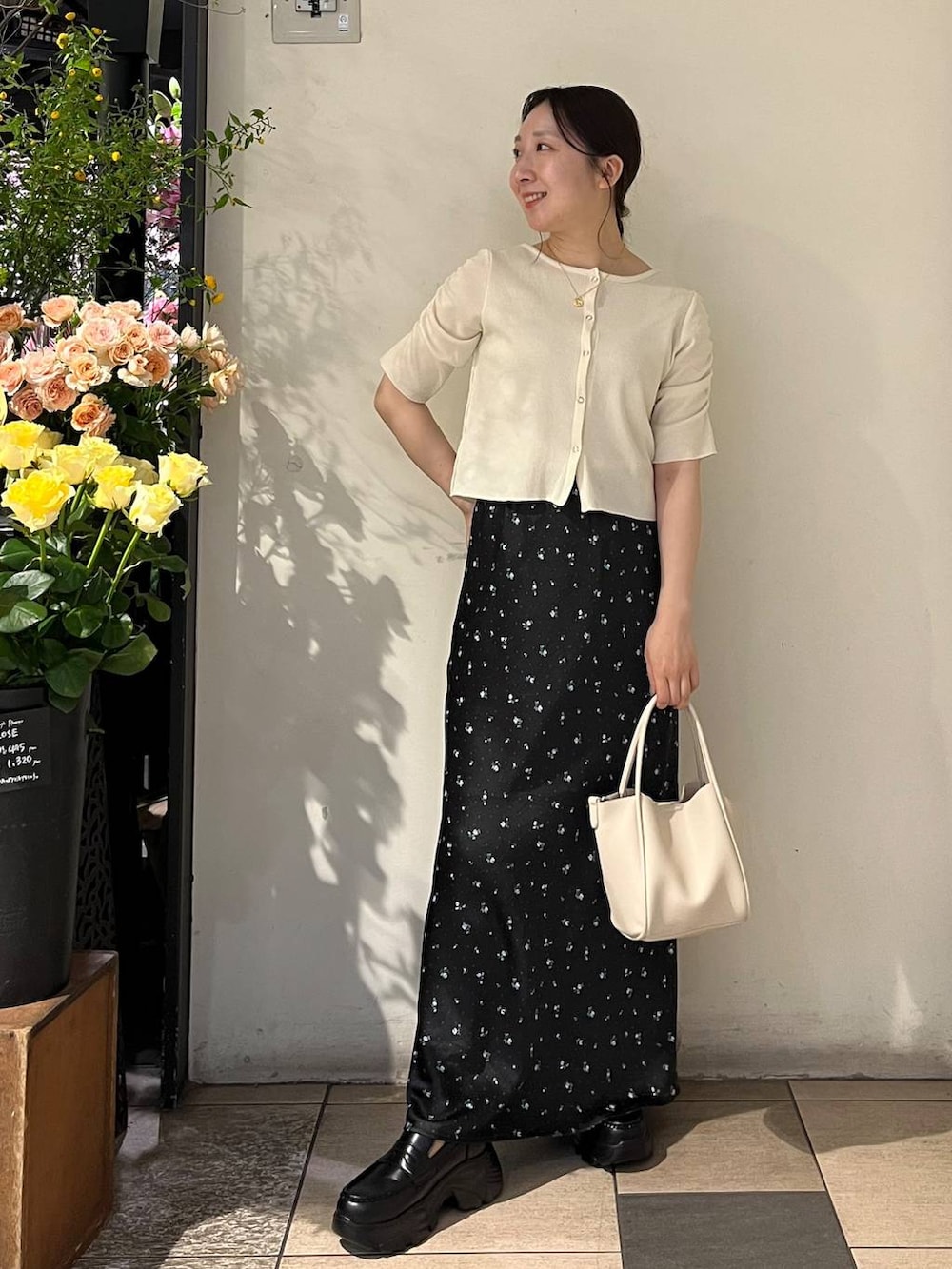 ブラック系のスカート、シルバー系のタンクトップ、ホワイト系のショルダーバッグを着用したレディースの春コーディネートの2枚目の写真