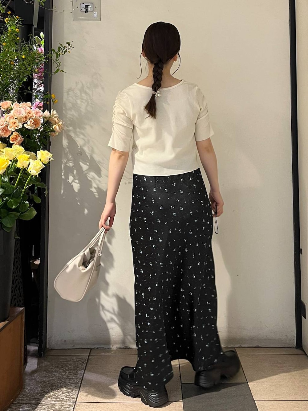 ブラック系のスカート、シルバー系のタンクトップ、ホワイト系のショルダーバッグを着用したレディースの春コーディネートの4枚目の写真