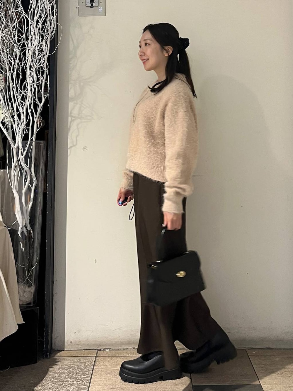 ブラック系のボストンバッグ、ブラウン系のスカート、ブラック系のブーツを着用したレディースの冬コーディネートの3枚目の写真
