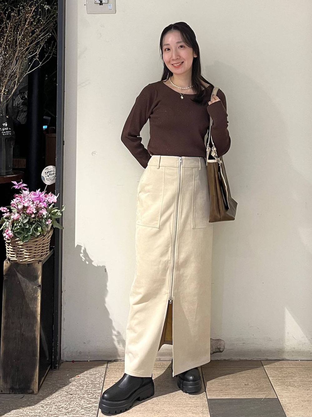 ホワイト系のスカート、ブラック系のブーツ、ブラウン系のニット/セーターを着用したレディースの冬コーディネートの2枚目の写真