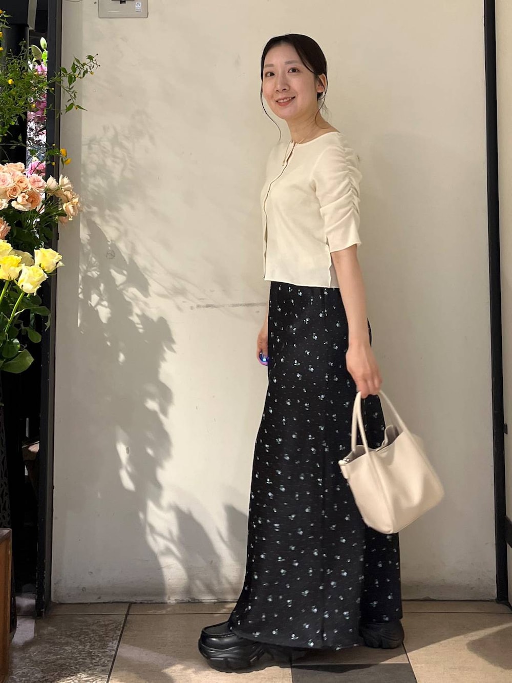 ブラック系のスカート、シルバー系のタンクトップ、ホワイト系のショルダーバッグを着用したレディースの春コーディネートの3枚目の写真