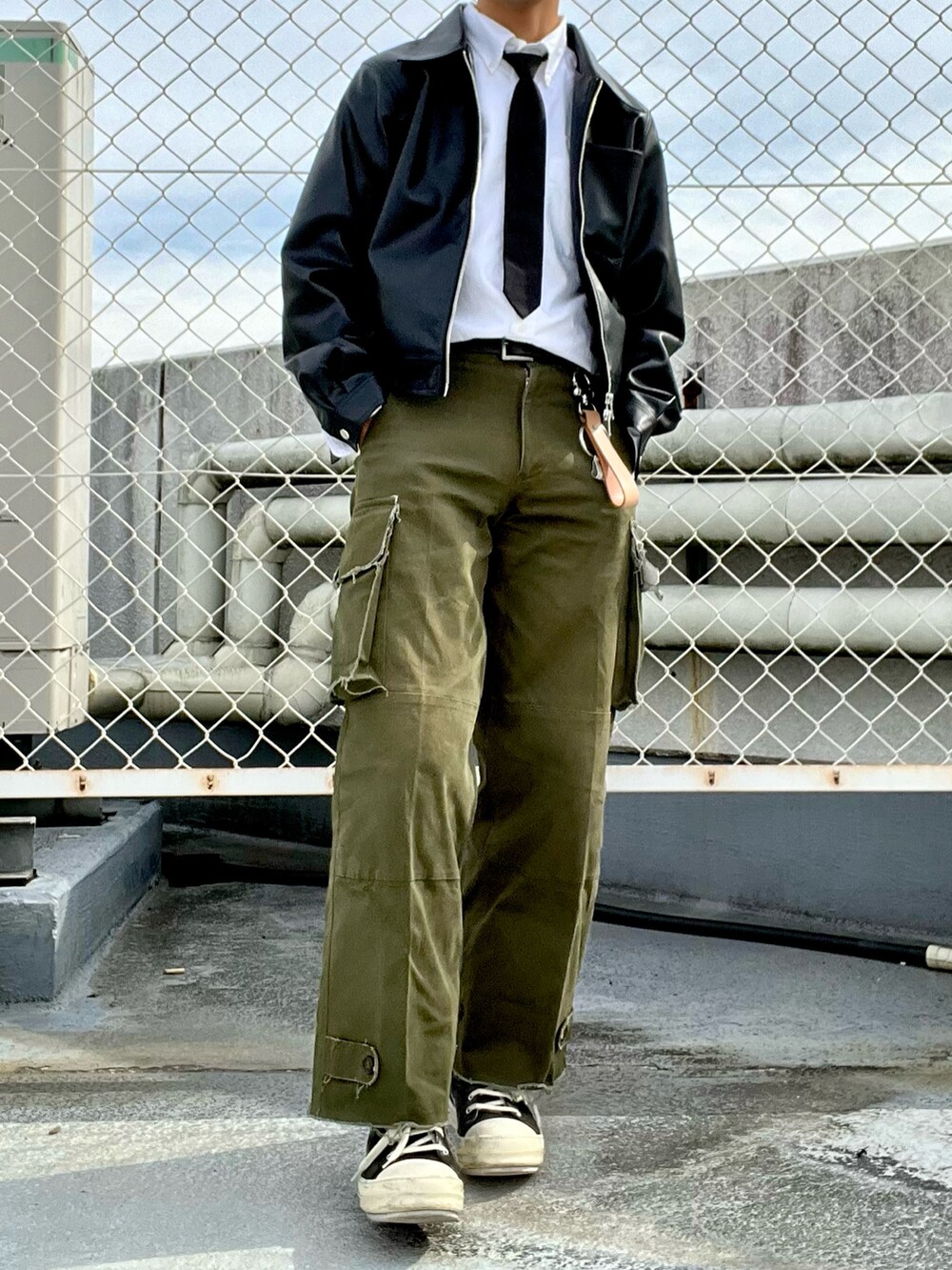 グリーン系のカーゴパンツ、ブラック系のスニーカー、ブラック系のライダースジャケットを着用したメンズの秋コーディネートの2枚目の写真