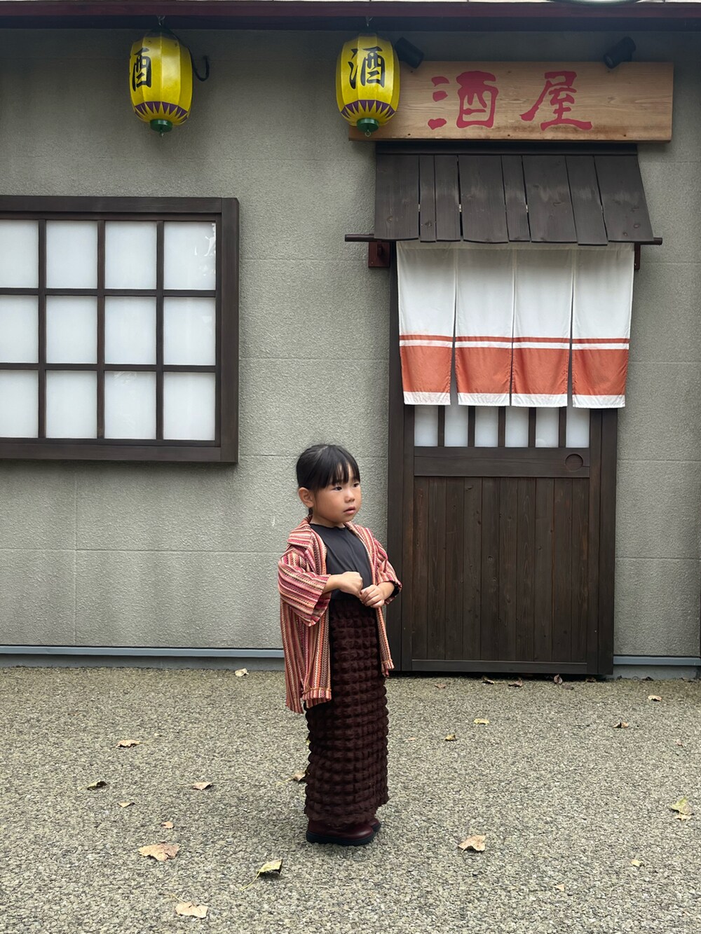 ブラウン系のスカート、オレンジ系のシャツ/ブラウスを着用したキッズの秋コーディネートの2枚目の写真