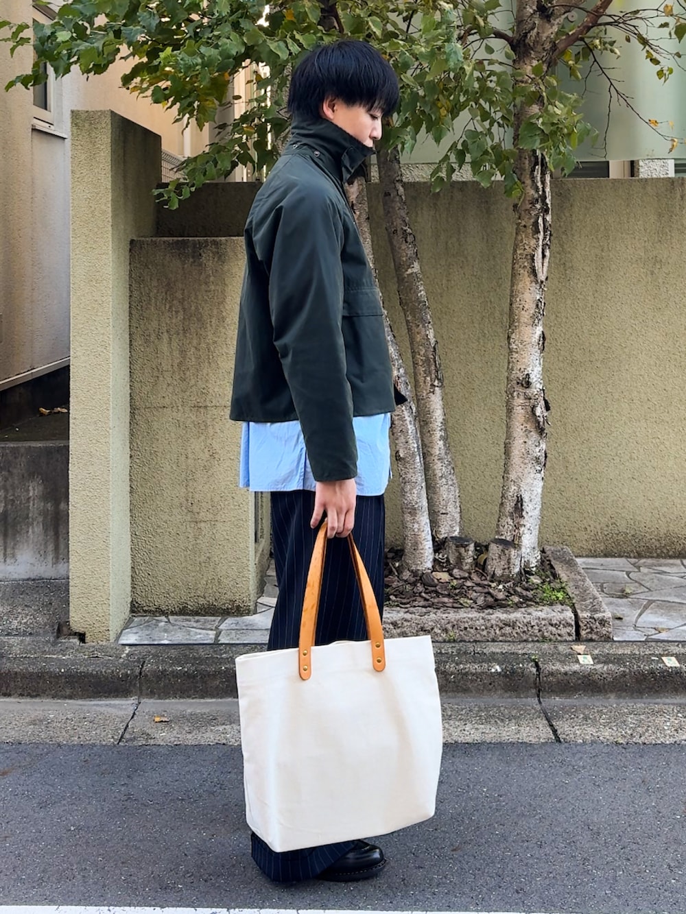 グリーン系のブルゾン、ブルー系のシャツ/ブラウス、ブラック系のスラックスを着用したメンズの秋コーディネートの4枚目の写真