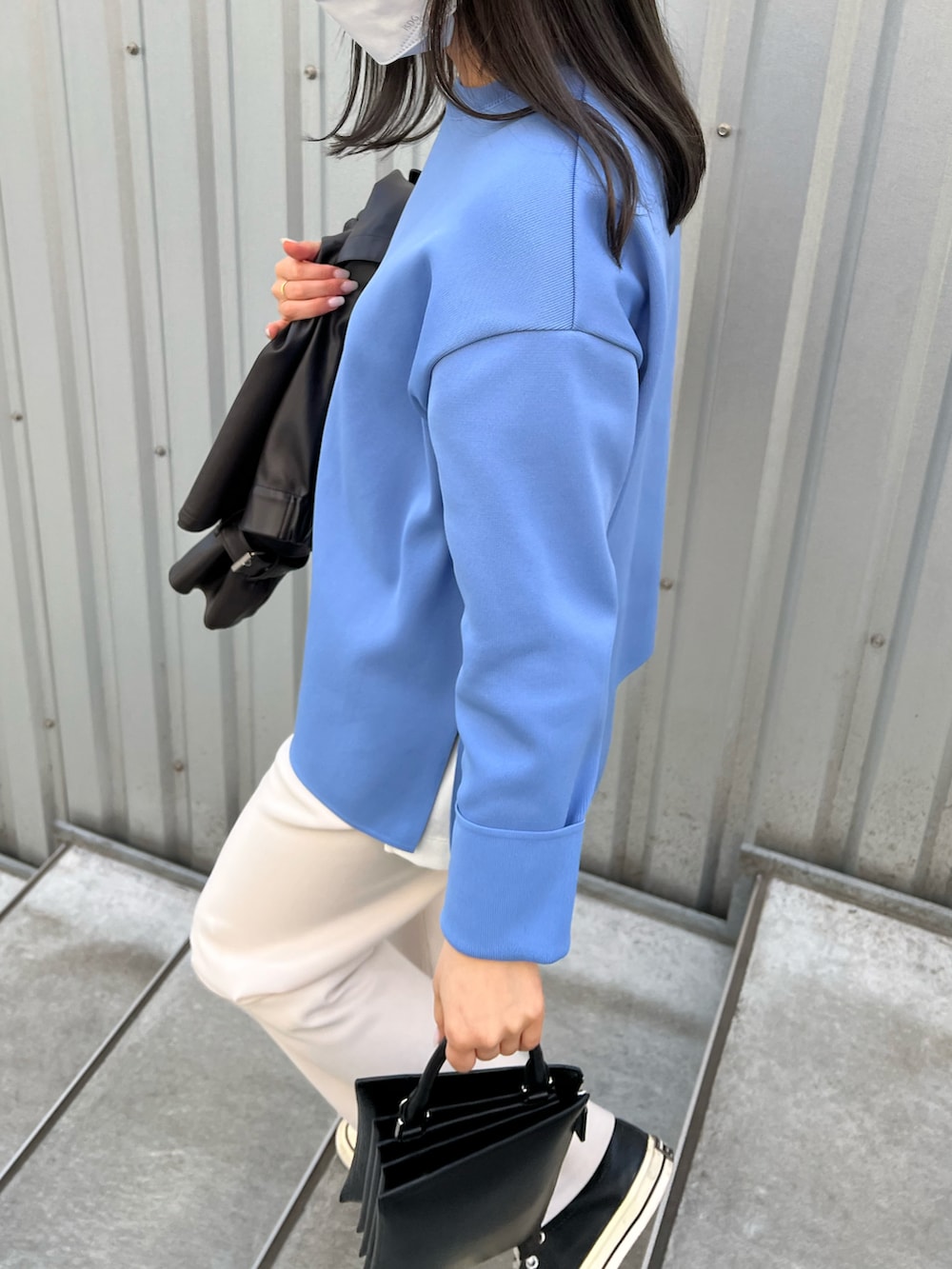 ブラック系のライダースジャケット、ホワイト系のスラックス、ブラック系のスニーカーを着用したレディースの春コーディネートの3枚目の写真