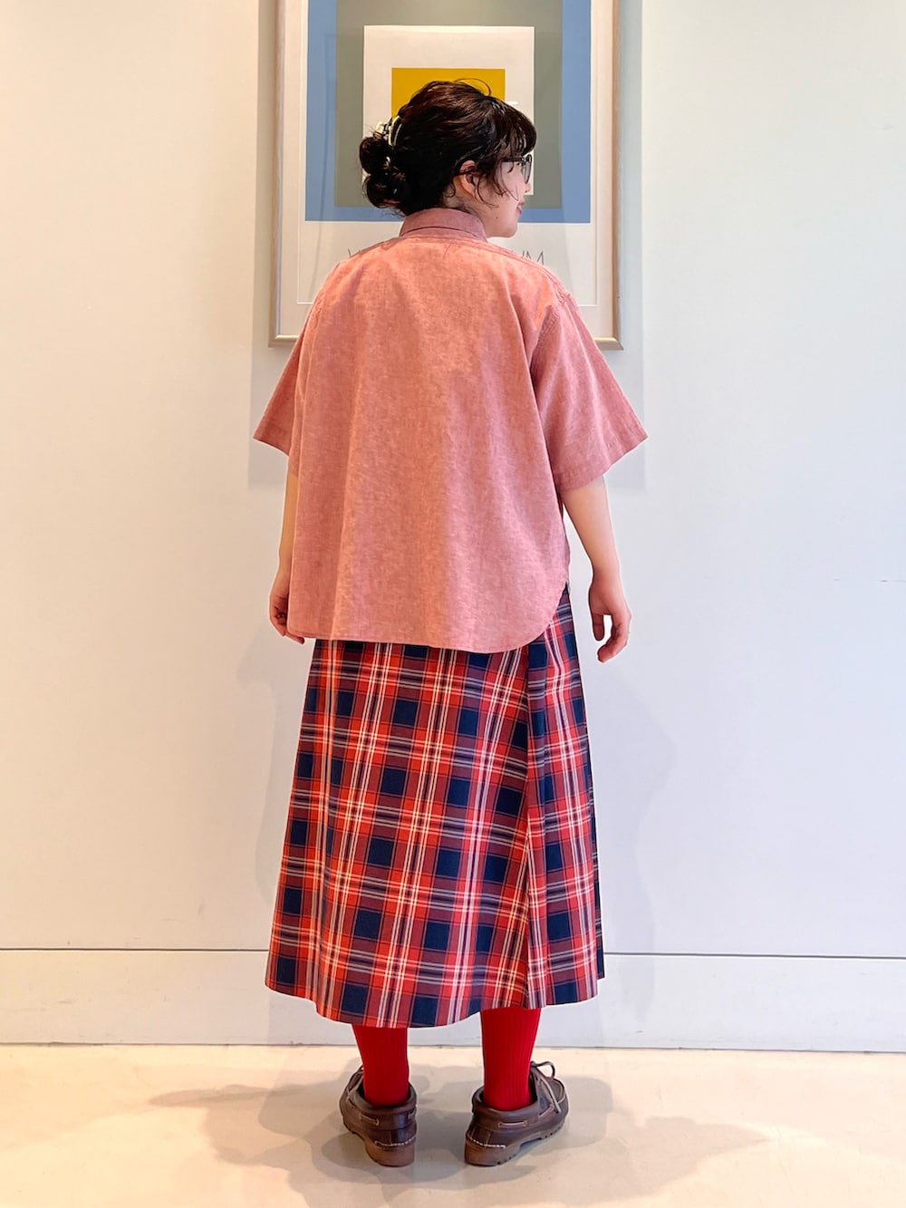 レッド系のシャツ/ブラウス、レッド系のスカート、ブラウン系のモカシン/デッキシューズを着用したレディースの春コーディネートの2枚目の写真