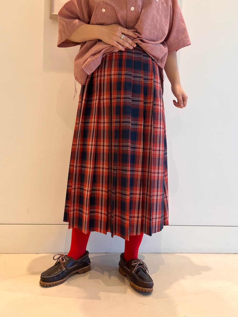 レッド系のシャツ/ブラウス、レッド系のスカート、ブラウン系のモカシン/デッキシューズを着用したレディースの春コーディネートの5枚目の写真