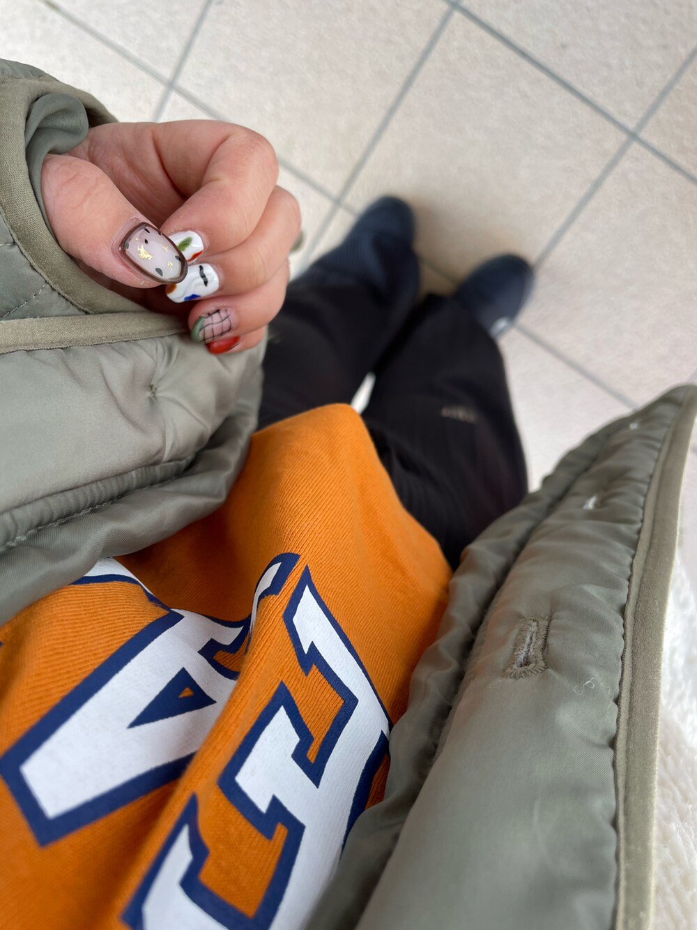 ブラック系のブーツ、ブラック系のパンツ、オレンジ系のTシャツ/カットソーを着用したレディースの冬コーディネートの2枚目の写真