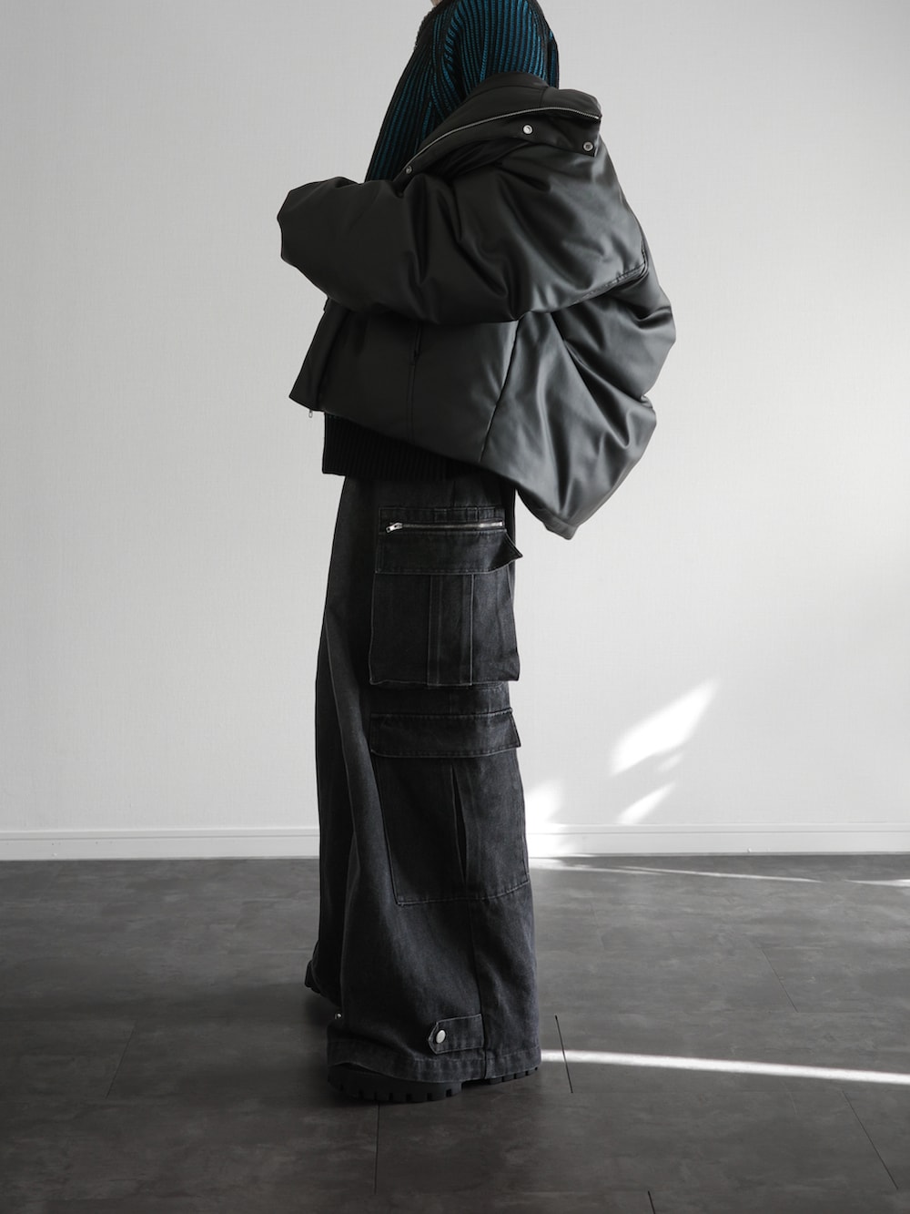 ブラック系のダウンジャケット/コート、ブルー系のニット/セーター、ブラック系のカーゴパンツを着用したメンズの冬コーディネートの2枚目の写真