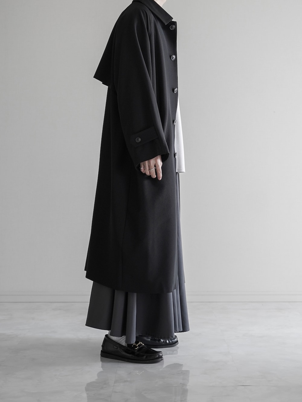 ブラック系のステンカラーコート、ホワイト系のTシャツ/カットソー、グレー系のスラックスを着用したメンズの秋コーディネートの3枚目の写真