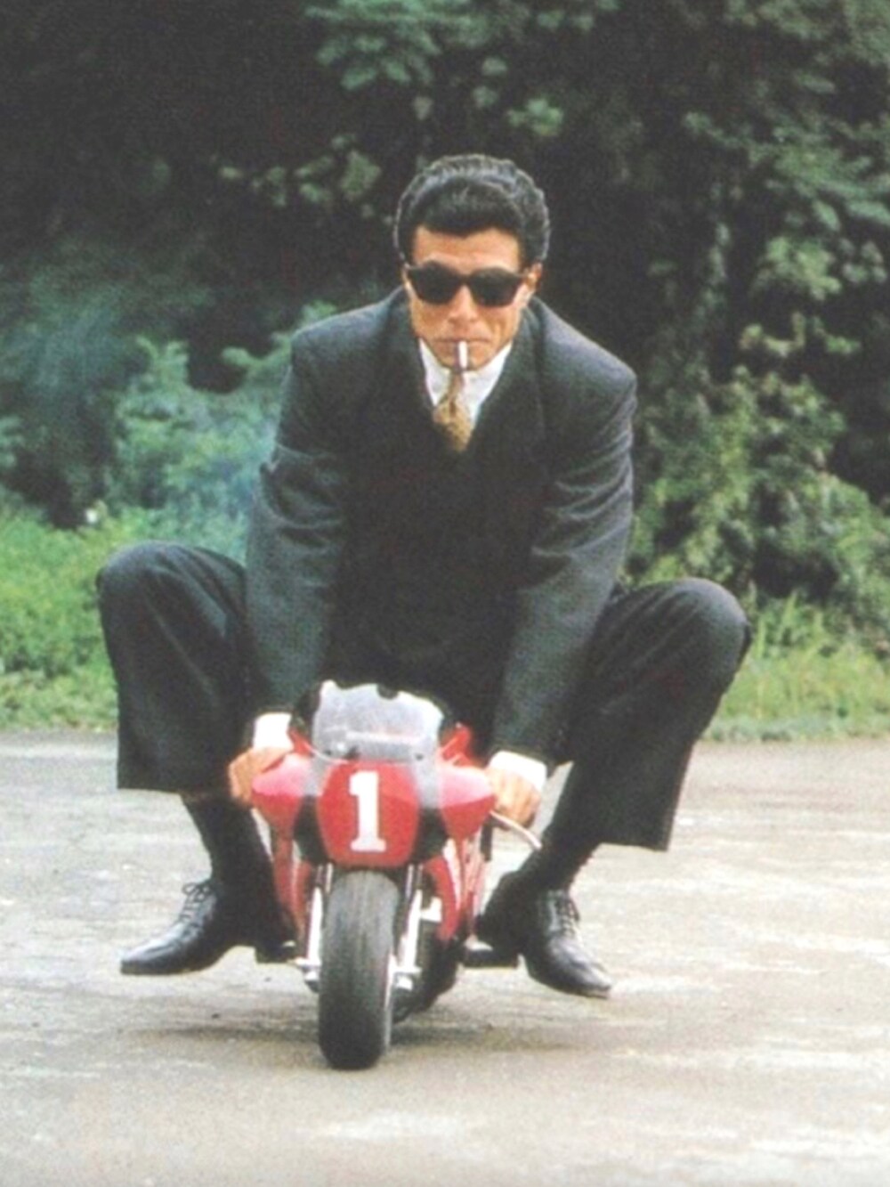 グリーン系のステンカラーコート、ブルー系のデニムパンツ、ブラック系のスニーカーを着用したメンズの秋コーディネートの5枚目の写真