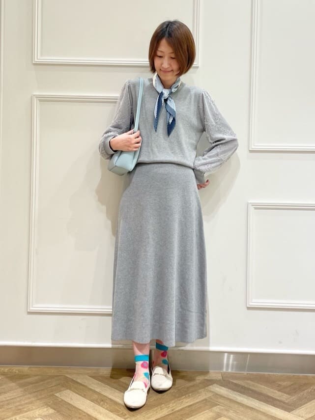 グレー系のニット/セーター、グレー系のスカート、ホワイト系のその他シューズを着用したレディースの春コーディネートの4枚目の写真