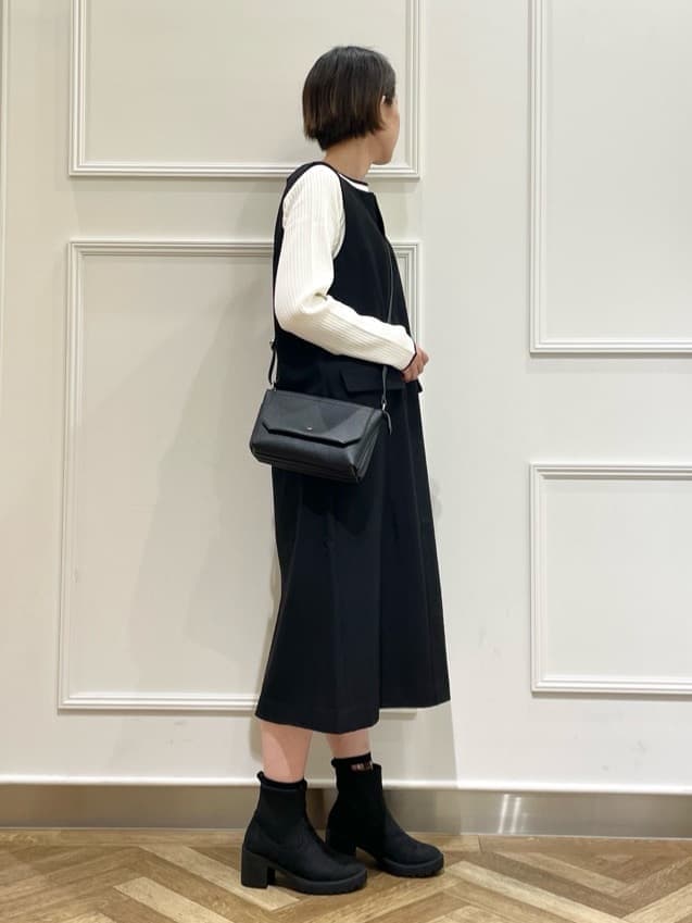 ブラック系のワンピース、ホワイト系のニット/セーター、ブラック系のブーツを着用したレディースの秋コーディネートの2枚目の写真