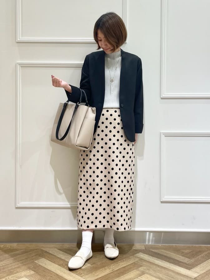 ブラック系のノーカラージャケット、グレー系のニット/セーター、ベージュ系のスカートを着用したレディースの春コーディネートの9枚目の写真