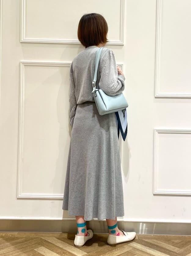 グレー系のニット/セーター、グレー系のスカート、ホワイト系のその他シューズを着用したレディースの春コーディネートの3枚目の写真