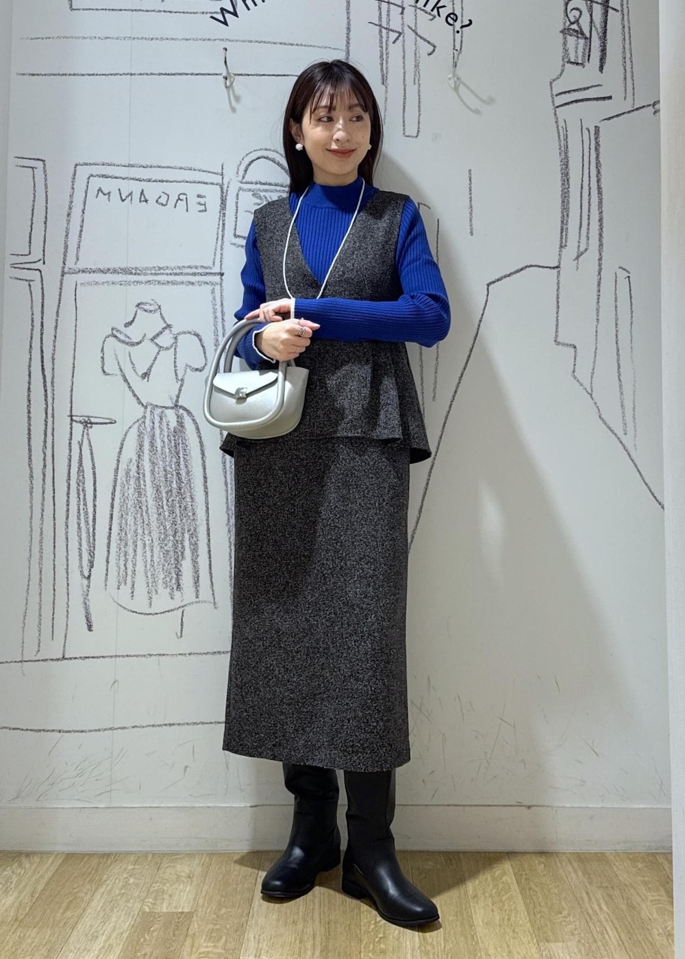 ブルー系のニット/セーター、ブラック系のブーツ、シルバー系のショルダーバッグを着用したレディースの冬コーディネートの3枚目の写真