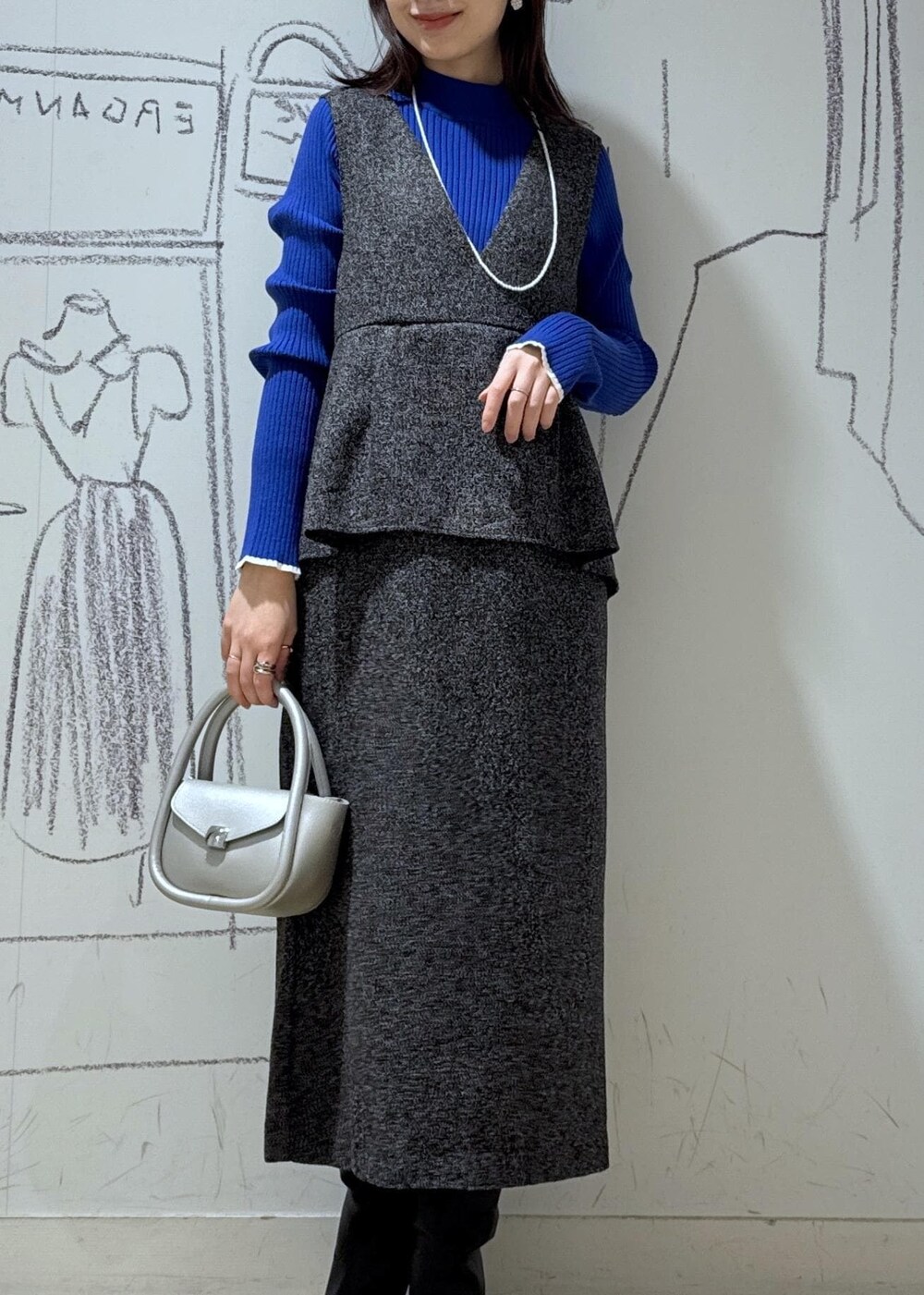 ブルー系のニット/セーター、ブラック系のブーツ、シルバー系のショルダーバッグを着用したレディースの冬コーディネートの2枚目の写真