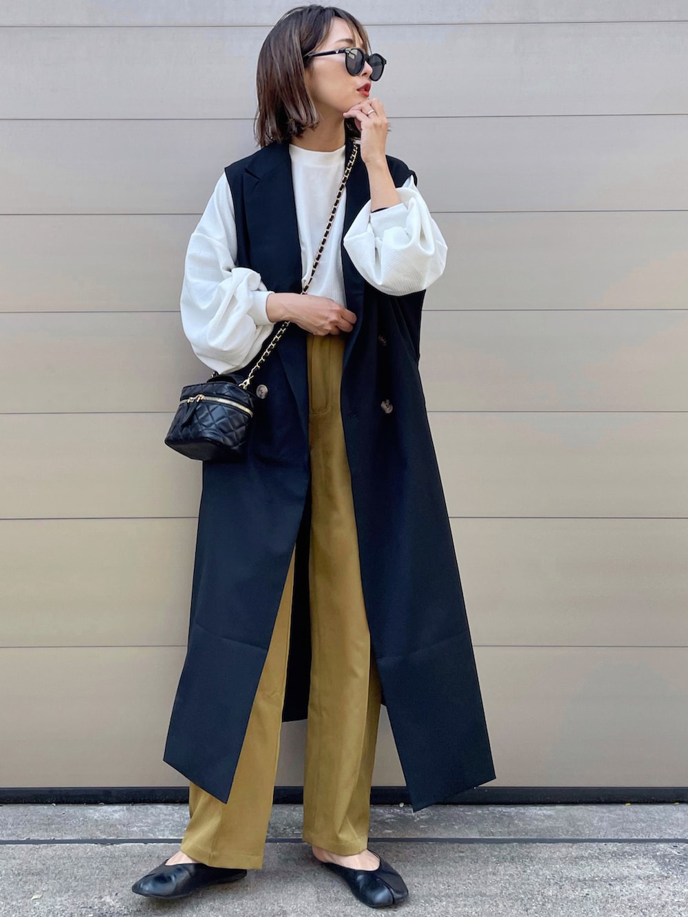 ブラック系のベストを着用したレディースの春コーディネートの2枚目の写真