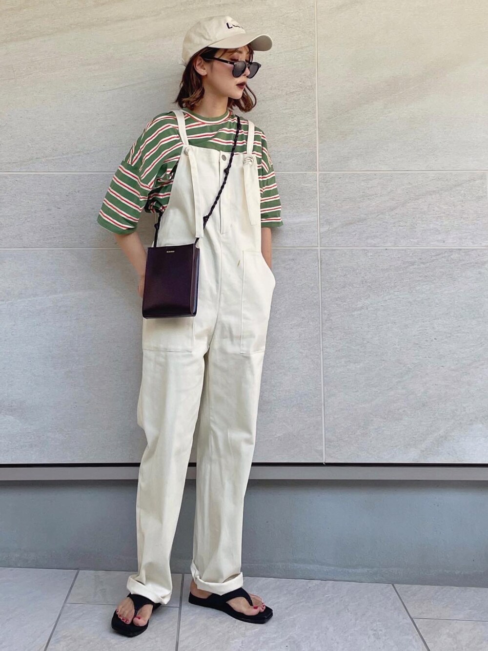 レッド系のショルダーバッグ、グリーン系のTシャツ/カットソー、ブラック系のサンダルを着用したレディースの春コーディネートの2枚目の写真