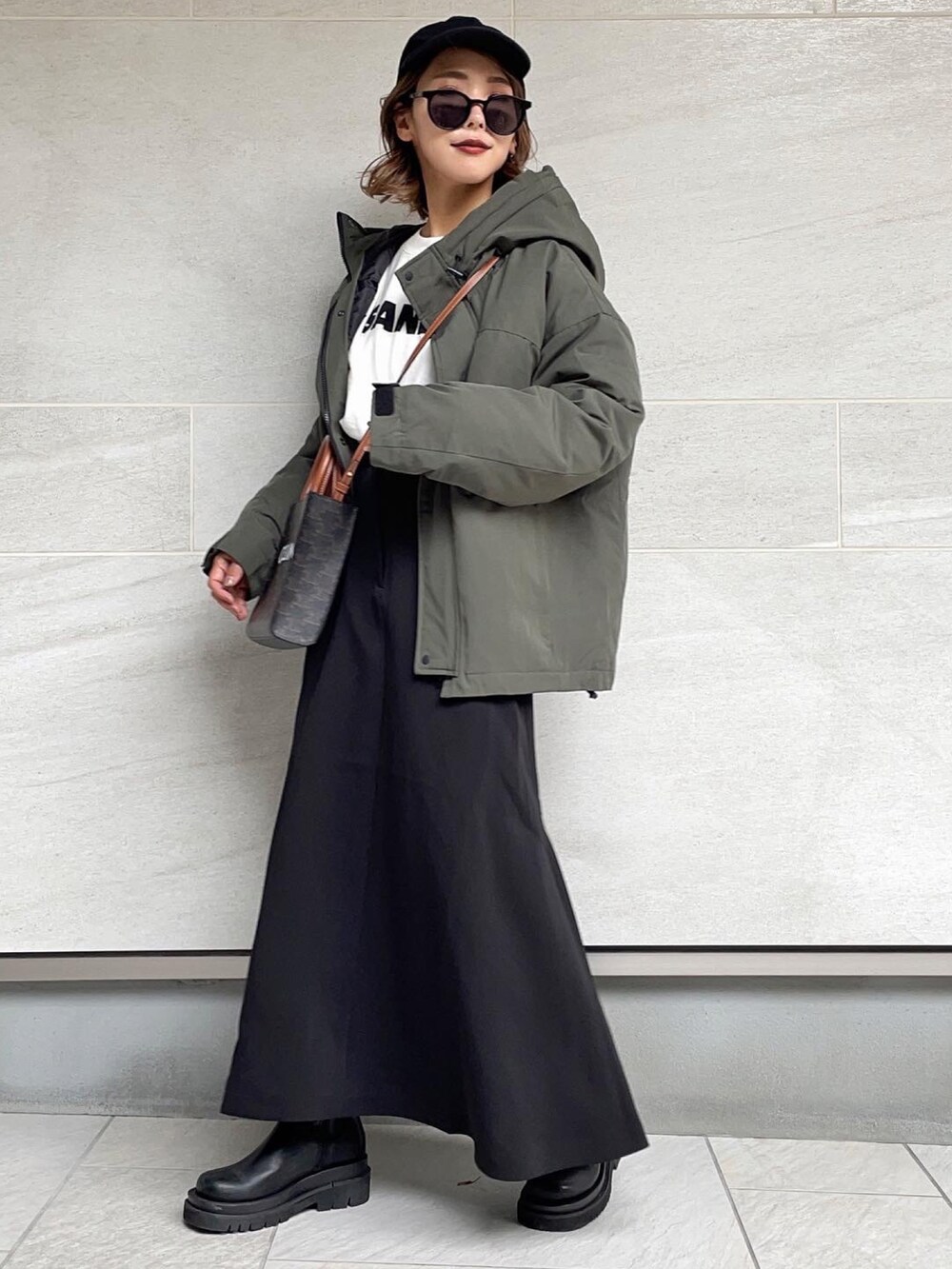 グリーン系のダウンジャケット/コート、ブラック系のスカート、ブラック系のブーツを着用したレディースの秋コーディネートの2枚目の写真