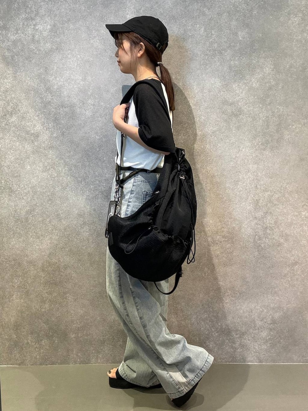 ブラック系のサンダル、ブルー系のデニムパンツ、ブラック系のバックパック/リュックを着用したレディースの夏コーディネートの2枚目の写真