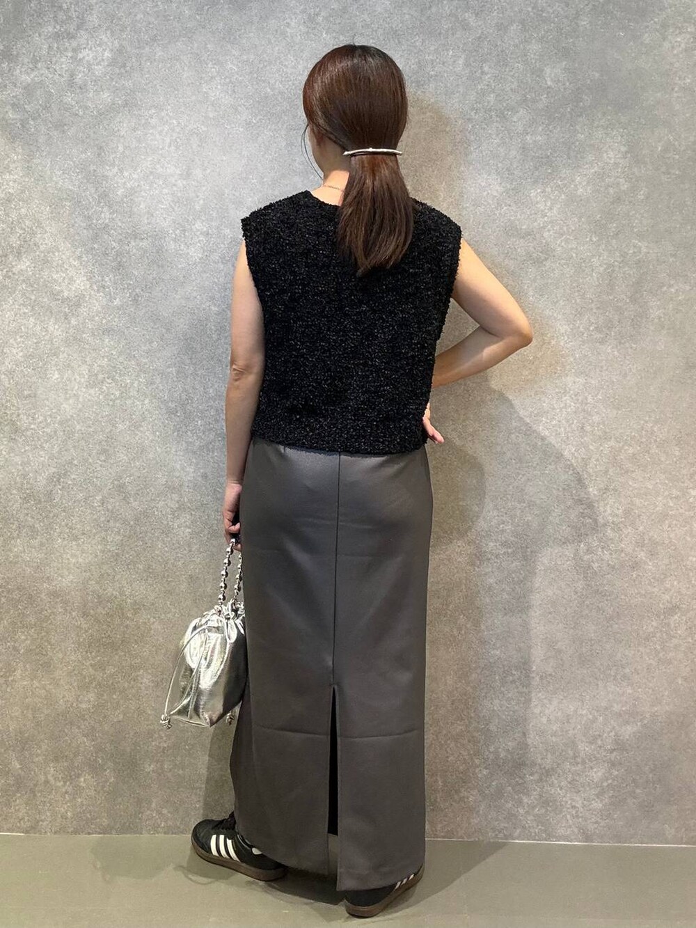 グレー系のスカート、ブラック系のベスト、シルバー系のショルダーバッグを着用したレディースの秋コーディネートの3枚目の写真