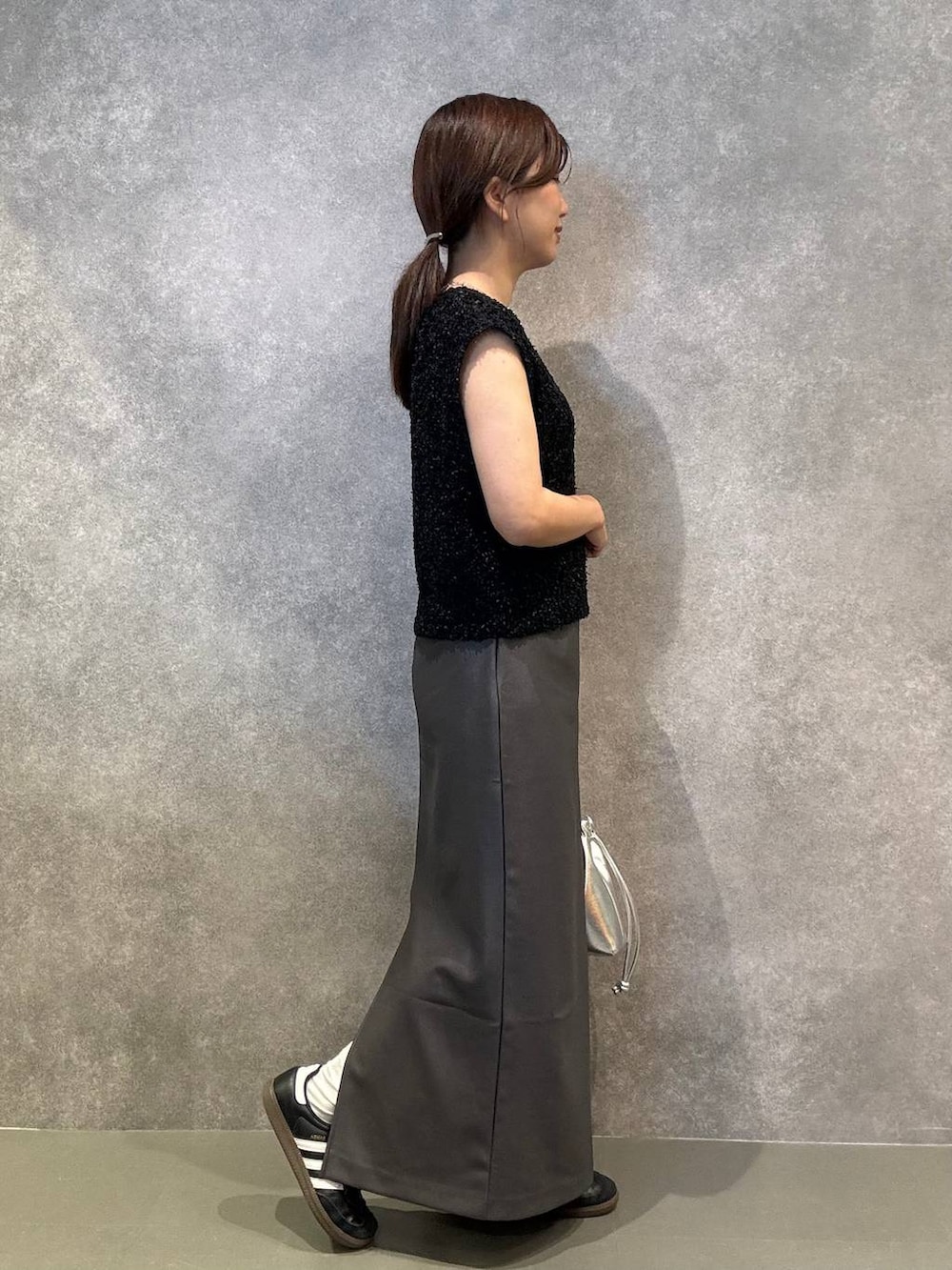 グレー系のスカート、ブラック系のベスト、シルバー系のショルダーバッグを着用したレディースの秋コーディネートの2枚目の写真