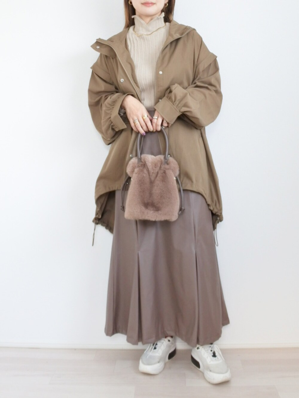 グリーン系のジャケット/アウター、ブラウン系のスカート、ベージュ系のニット/セーターを着用したレディースの秋コーディネートの2枚目の写真