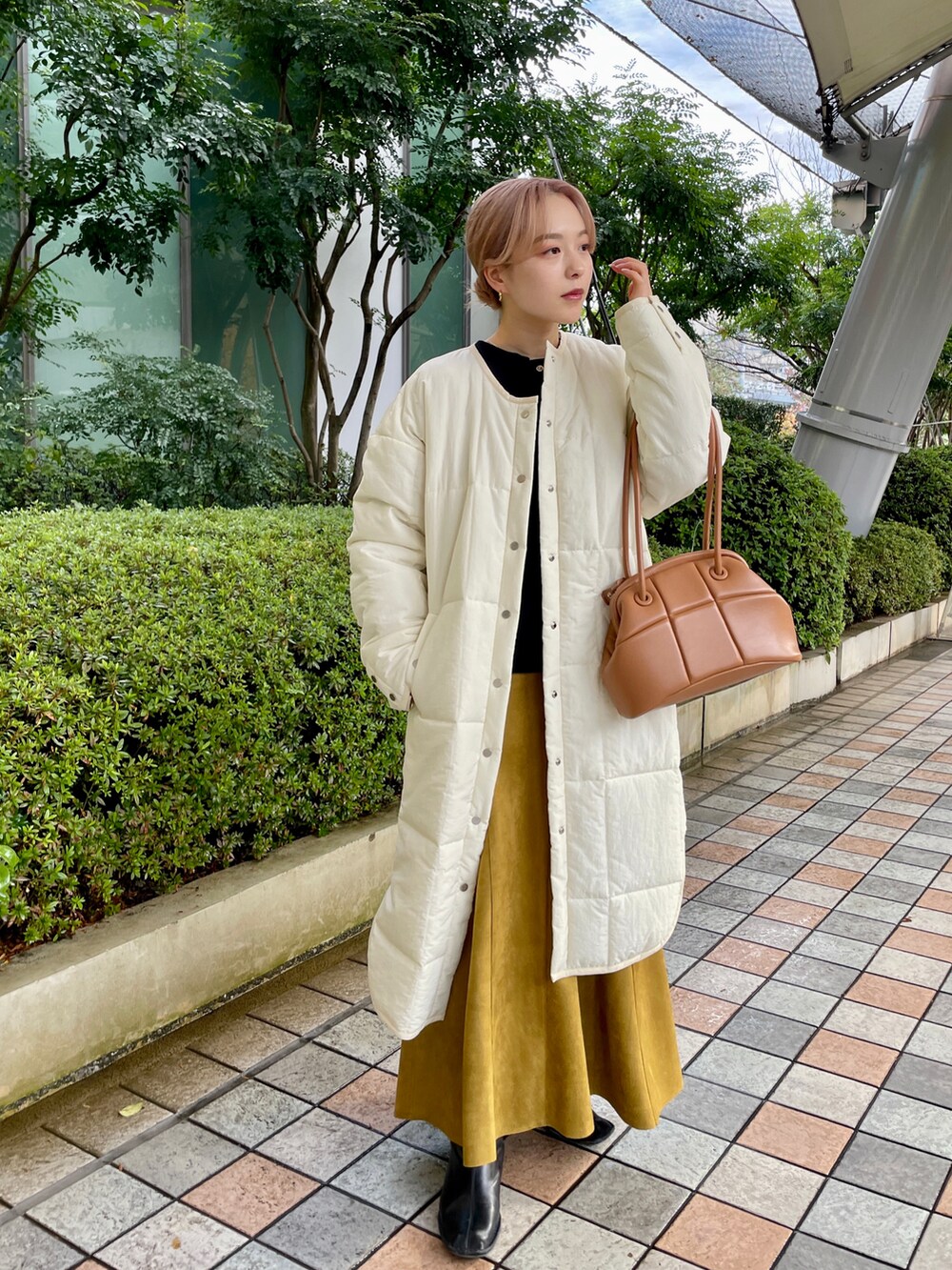 ホワイト系のノーカラーコート、ブラック系のブーツ、ブラック系のトートバッグを着用したレディースの冬コーディネートの2枚目の写真