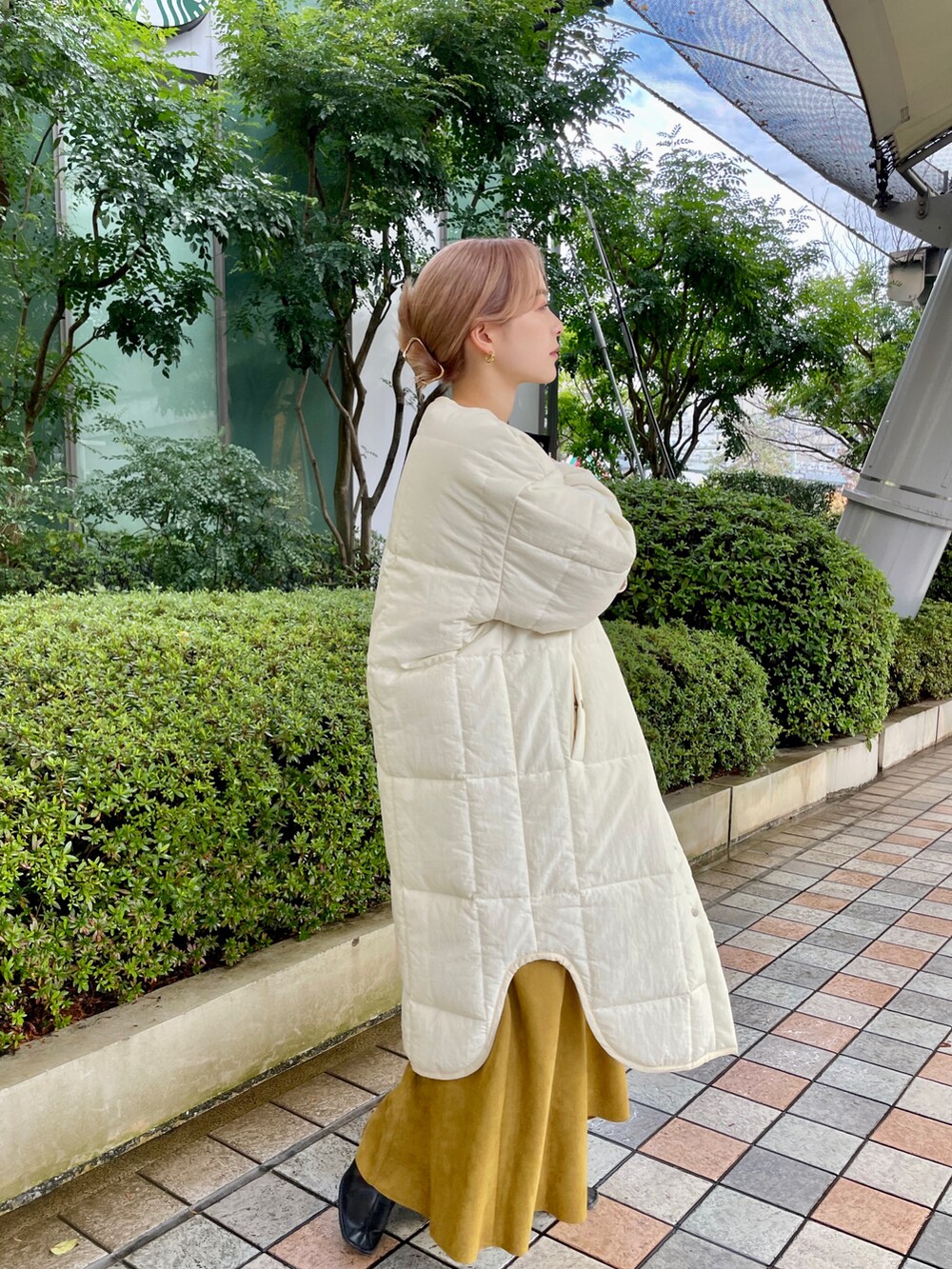 ホワイト系のノーカラーコート、ブラック系のブーツ、ブラック系のトートバッグを着用したレディースの冬コーディネートの3枚目の写真