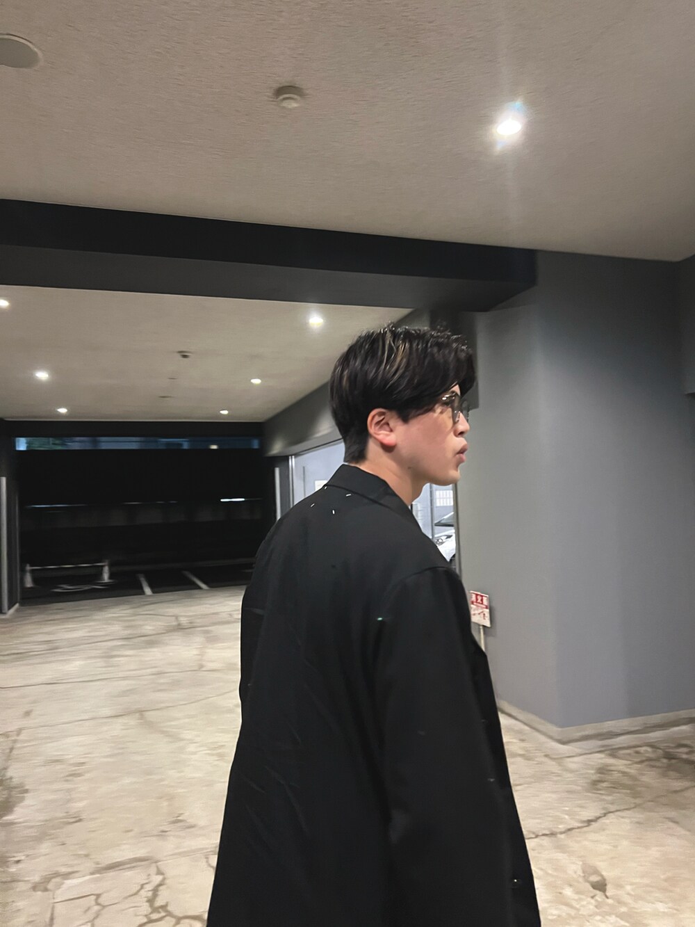 ブラック系のブルゾン、ブラウン系のTシャツ/カットソー、ベージュ系のスラックスを着用したメンズの春コーディネートの3枚目の写真