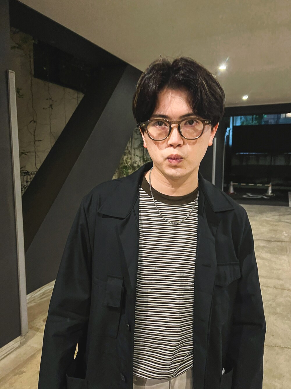 ブラック系のブルゾン、ブラウン系のTシャツ/カットソー、ベージュ系のスラックスを着用したメンズの春コーディネートの4枚目の写真