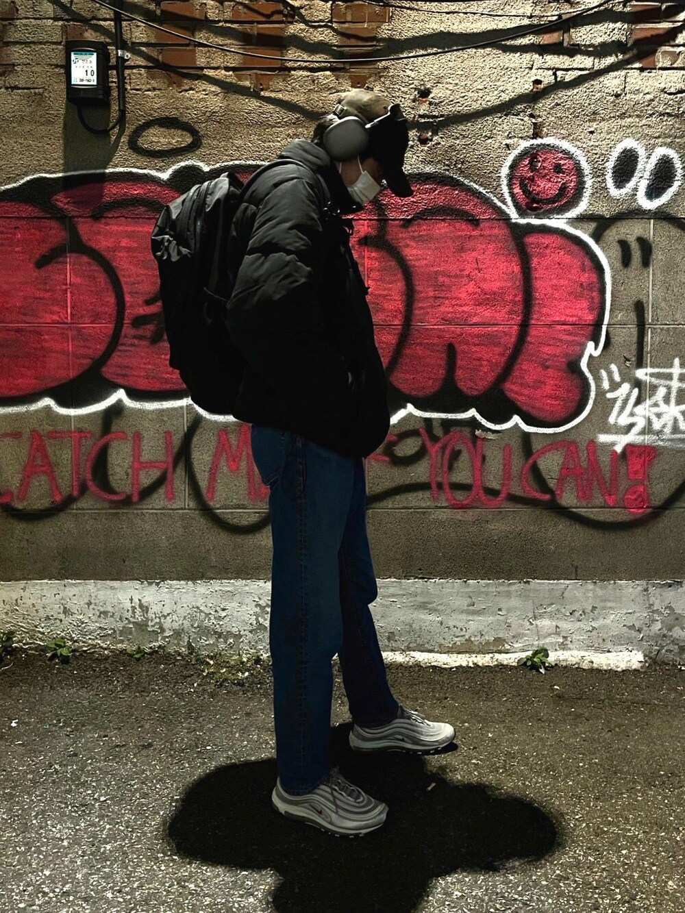 ブルー系のデニムパンツ、ブラック系のダウンジャケット/コート、ブラック系のバックパック/リュックを着用したメンズの秋コーディネートの2枚目の写真