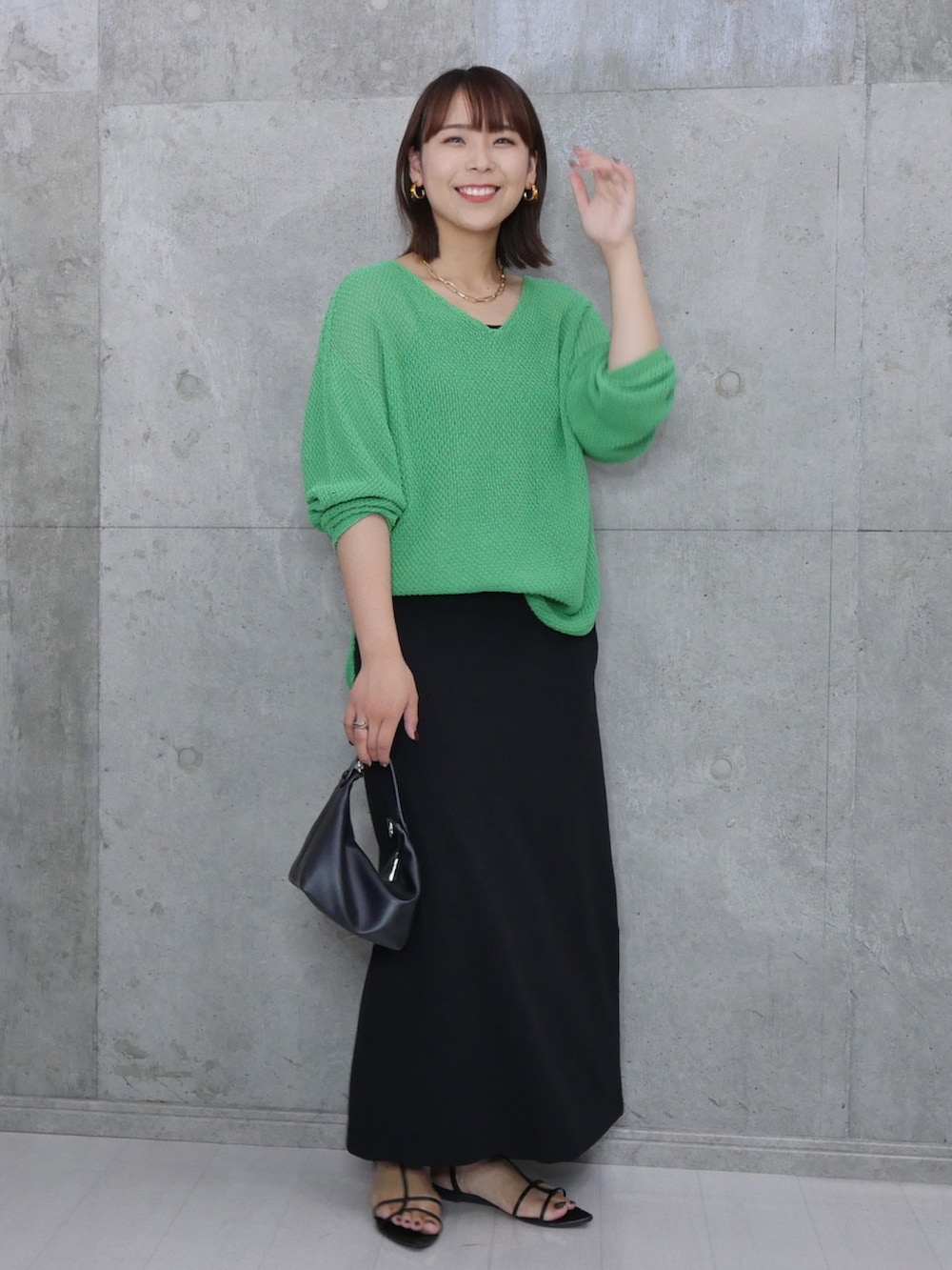 グリーン系のニット/セーター、ブラック系のハンドバッグ、ブラック系のサンダルを着用したレディースの秋コーディネートの3枚目の写真