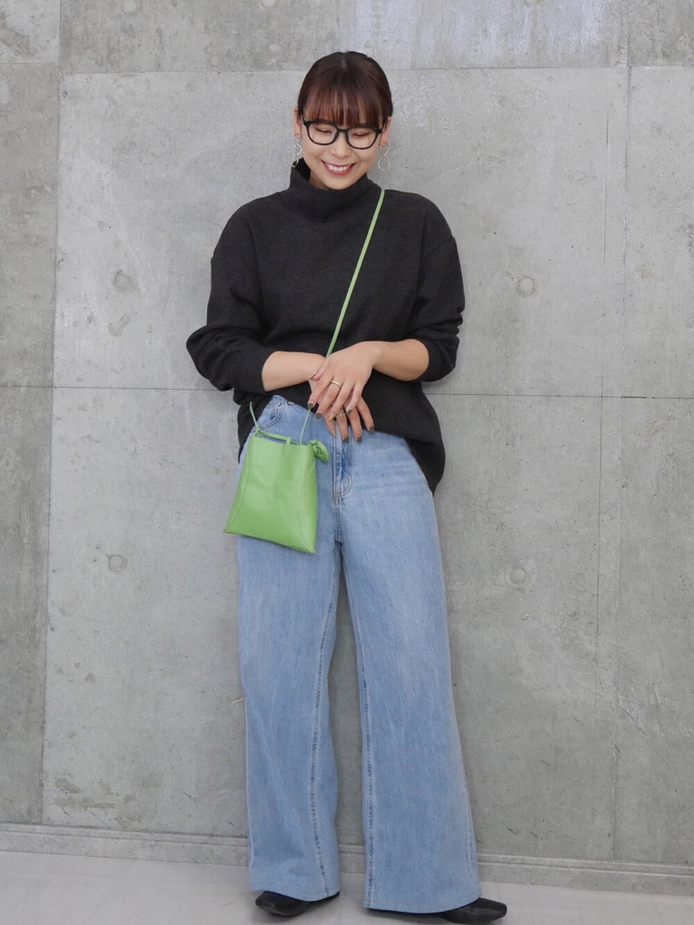 ブルー系のデニムパンツ、ブラック系のブーツ、グリーン系のバッグを着用したレディースの秋コーディネートの3枚目の写真