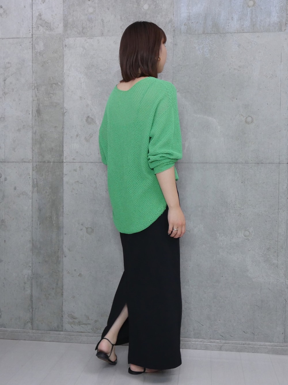 グリーン系のニット/セーター、ブラック系のハンドバッグ、ブラック系のサンダルを着用したレディースの秋コーディネートの2枚目の写真