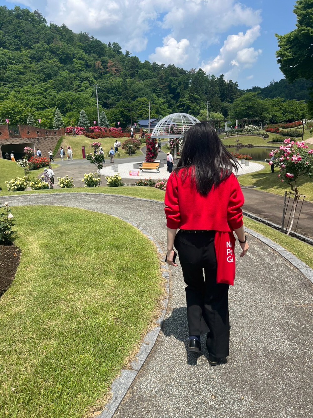 レッド系のカーディガン/ボレロ、ブラック系のスラックス、ブラック系のローファーを着用したレディースの秋コーディネートの2枚目の写真