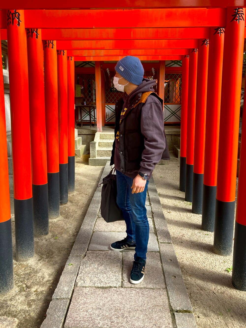 ブラウン系のパーカー、ブルー系のデニムパンツ、ブラック系のスニーカーを着用したメンズの春コーディネートの2枚目の写真