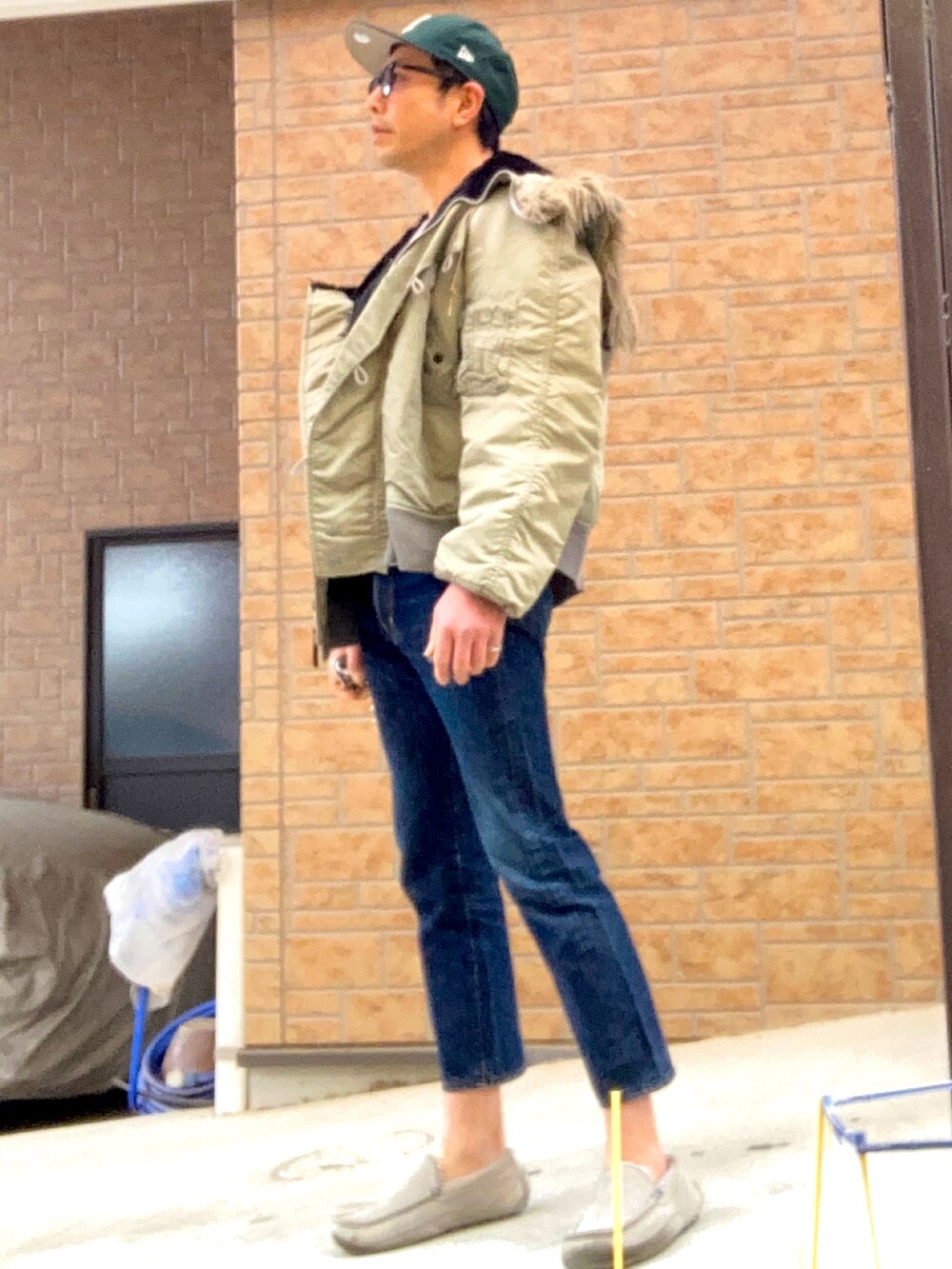 ブルー系のデニムパンツ、グレー系のスリッポン、シルバー系のミリタリージャケットを着用したメンズの冬コーディネートの2枚目の写真