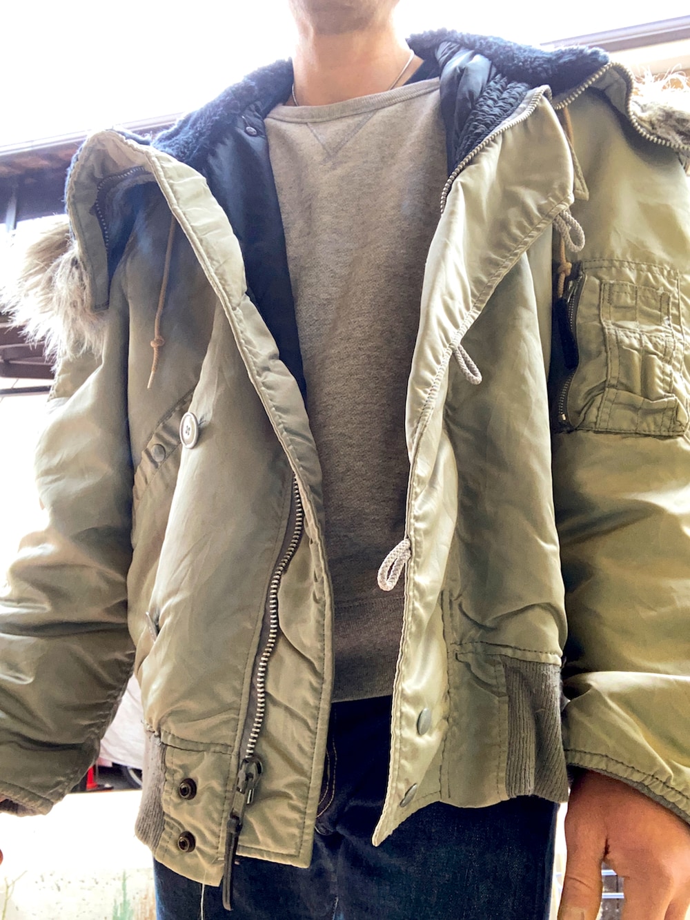 ブルー系のデニムパンツ、グレー系のスリッポン、シルバー系のミリタリージャケットを着用したメンズの冬コーディネートの3枚目の写真