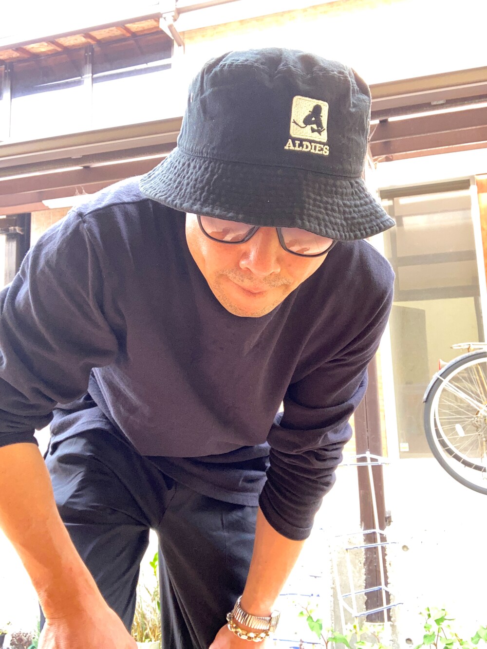 ブラック系のチノパンツ、ブラック系のTシャツ/カットソー、ブラック系のサンダルを着用したメンズの春コーディネートの3枚目の写真