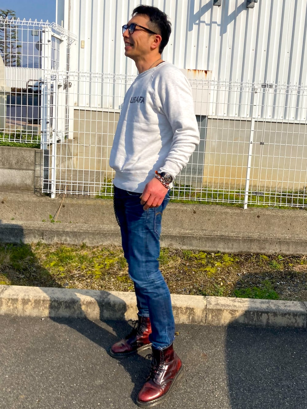 ブルー系のデニムパンツ、ホワイト系のスウェット、レッド系のブーツを着用したメンズの春コーディネートの2枚目の写真