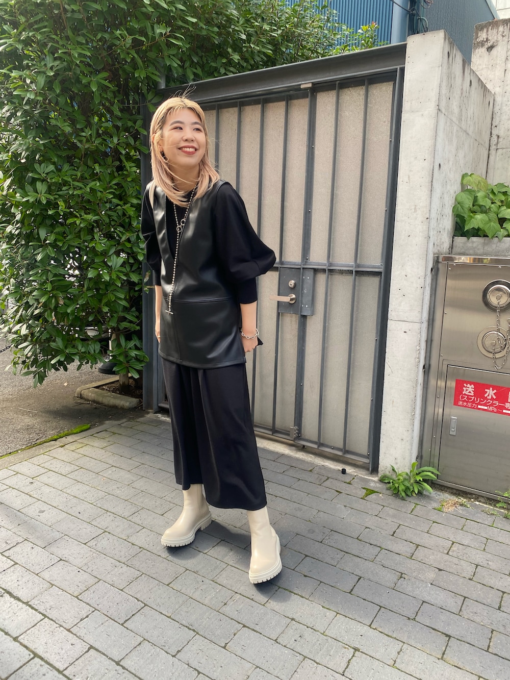 ブラック系のワンピース、ブラック系のベスト、ホワイト系のブーツを着用したレディースの秋コーディネートの3枚目の写真