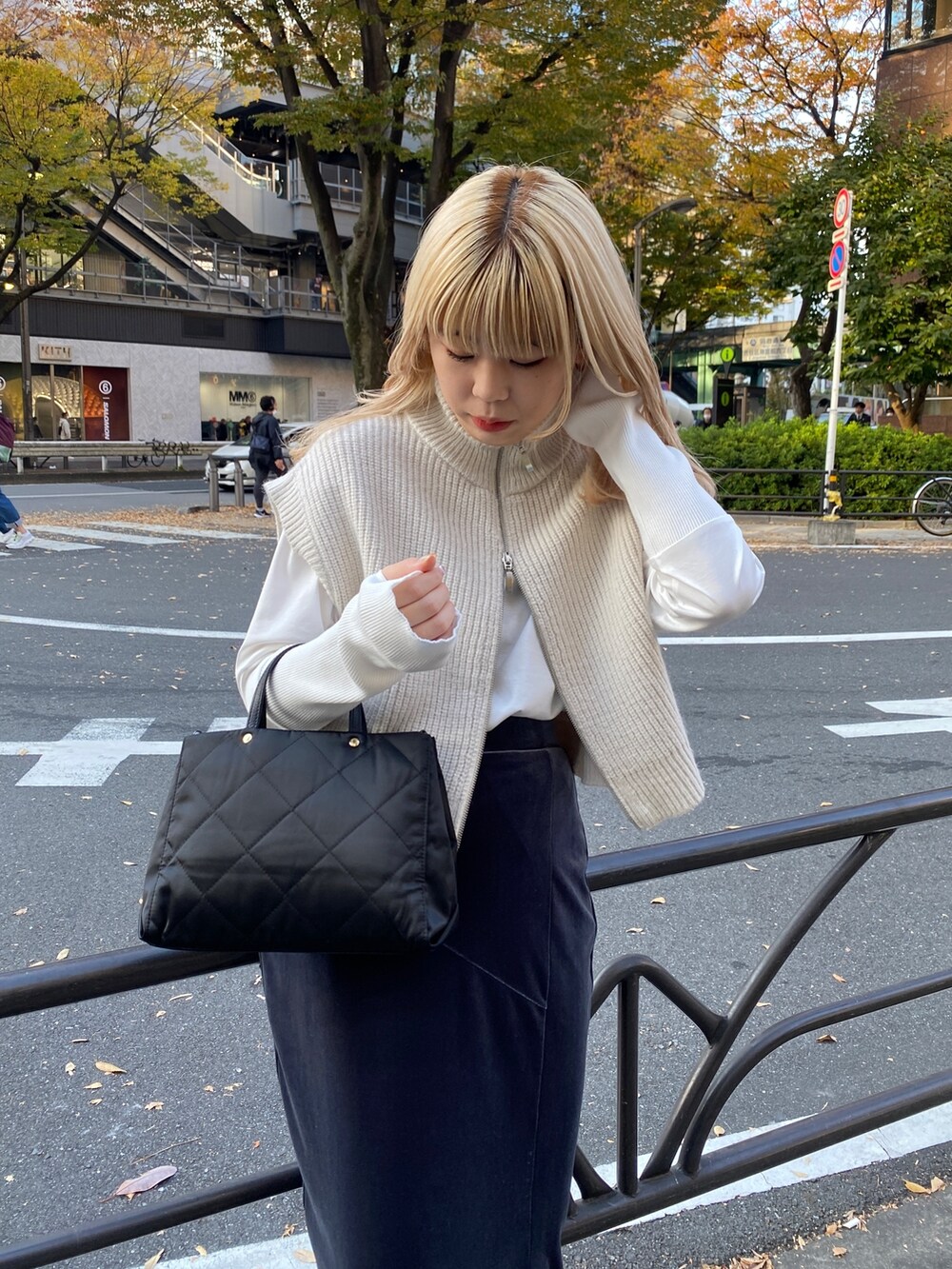 グレー系のスカート、ホワイト系のベスト、ホワイト系のTシャツ/カットソーを着用したレディースの秋コーディネートの4枚目の写真